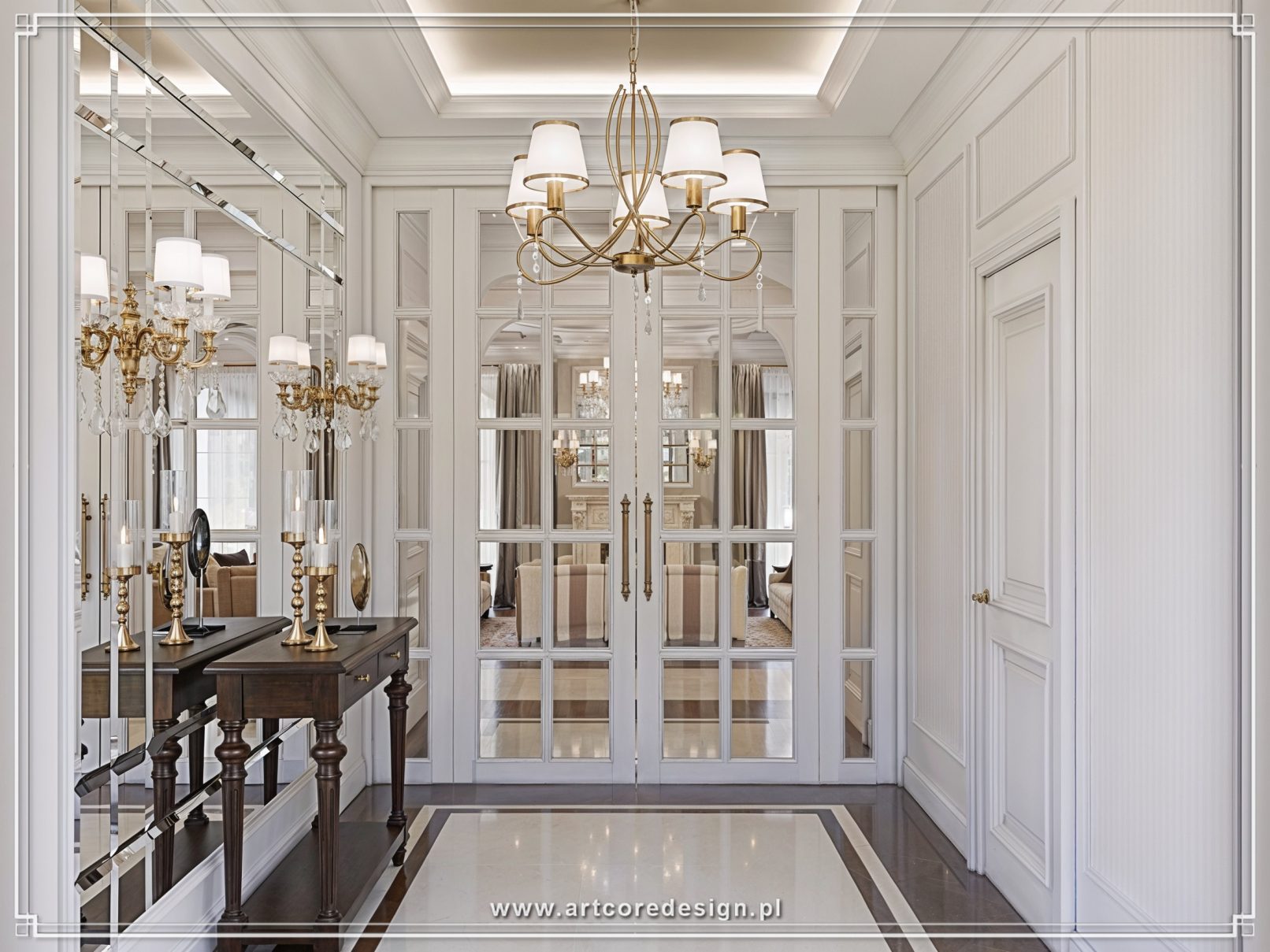 Elegancki hol wejściowy w stylu klasycznym z lustrzaną ścianą, konsolą i przeszklonymi drzwiami prowadzącymi do salonu. Jasne wnętrze domu z dekoracyjną sztukaterią i stylowym oświetleniem.